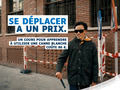 Personne utilisant une canne blanche en ville. Slogan : « Se déplacer a un prix. »